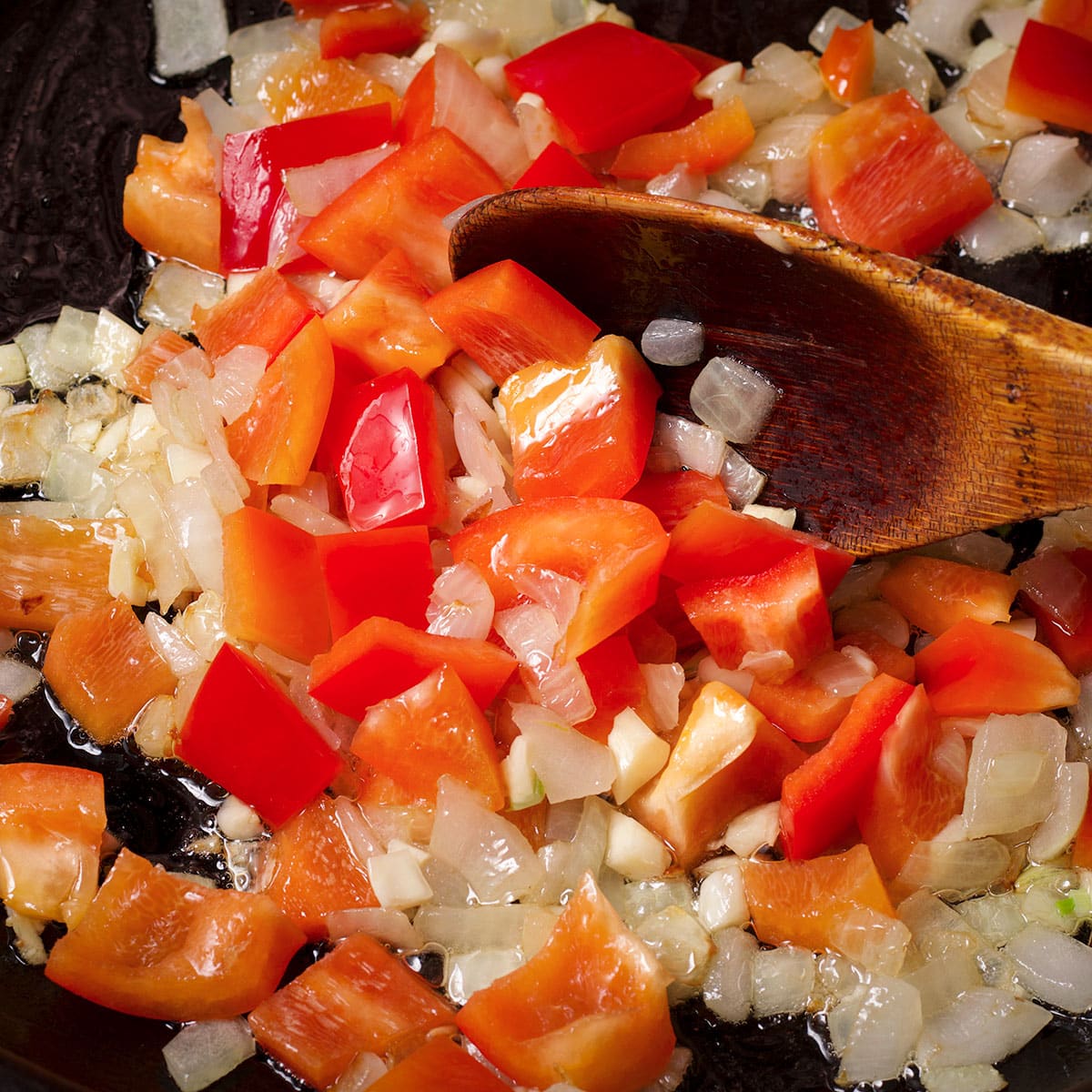 Add chopped red bell pepper and garlic to the skillet with the onion.