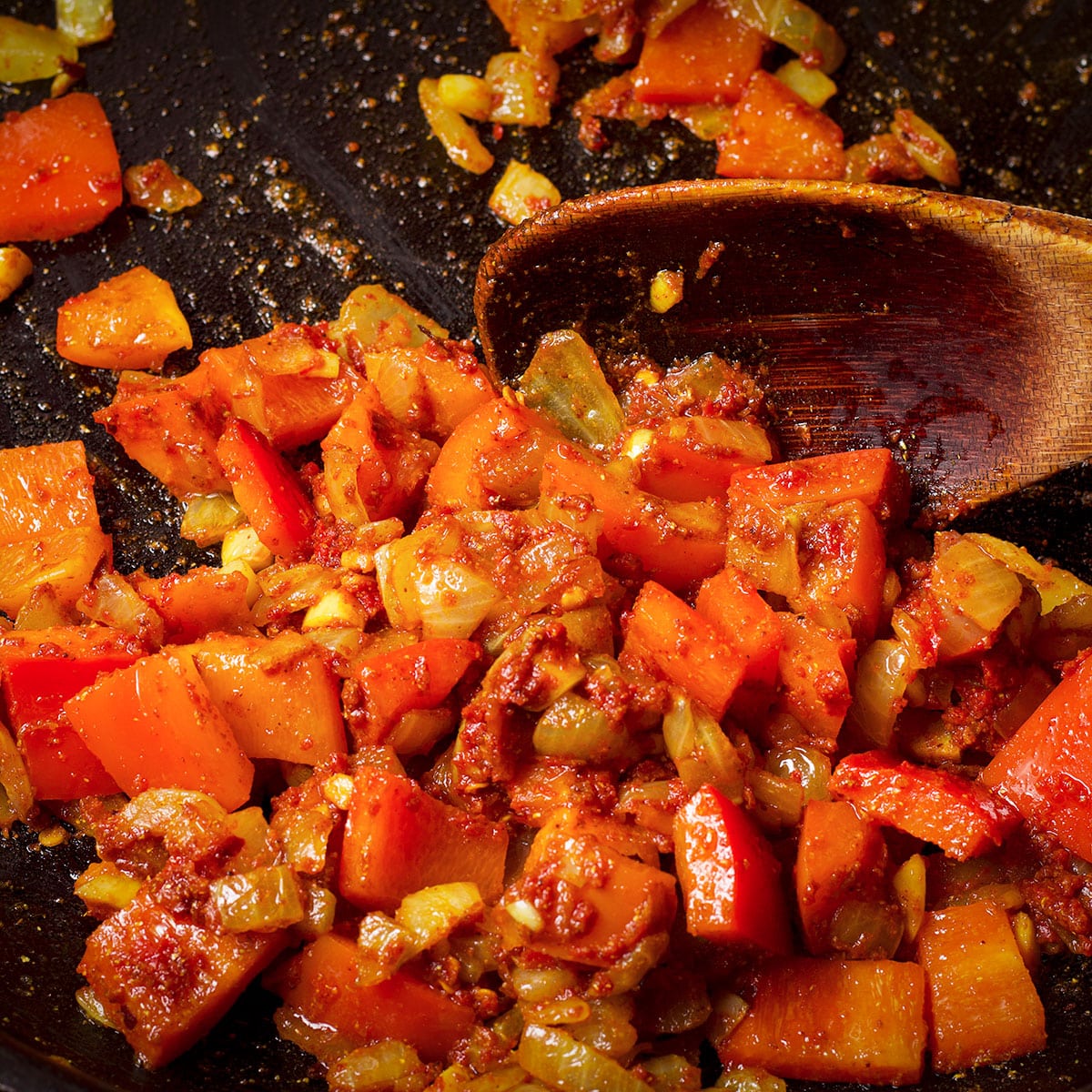 Stir tomato paste and curry powder into the chopped onions, bell pepper, and garlic.