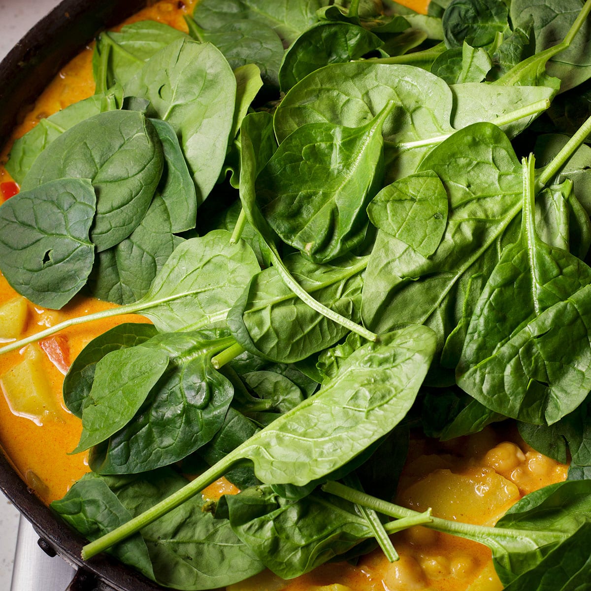 Add fresh spinach to the curry while it simmers.