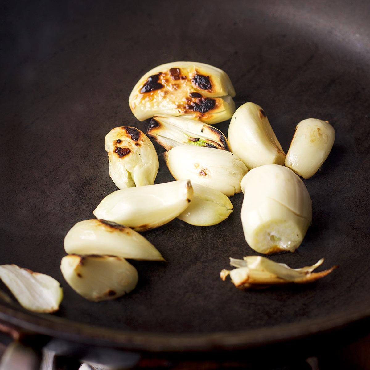 Ten cloves of garlic cooking in a small skillet until charred. 