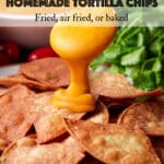 Pouring nacho cheese sauce over a plate of homemade tortilla chips.