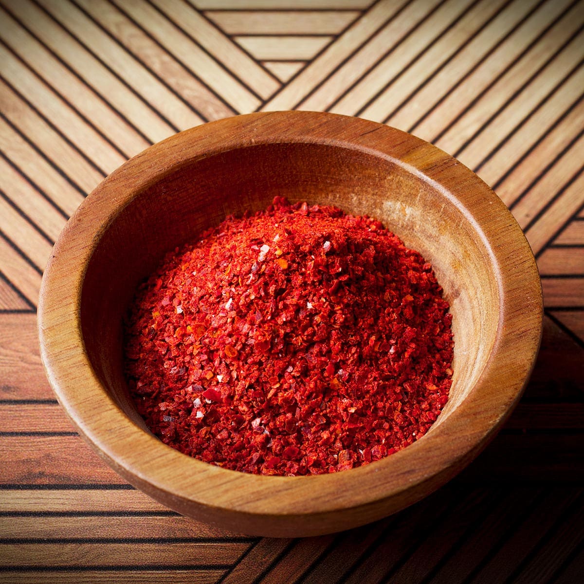 A small wooden bowl containing Aleppo pepper.
