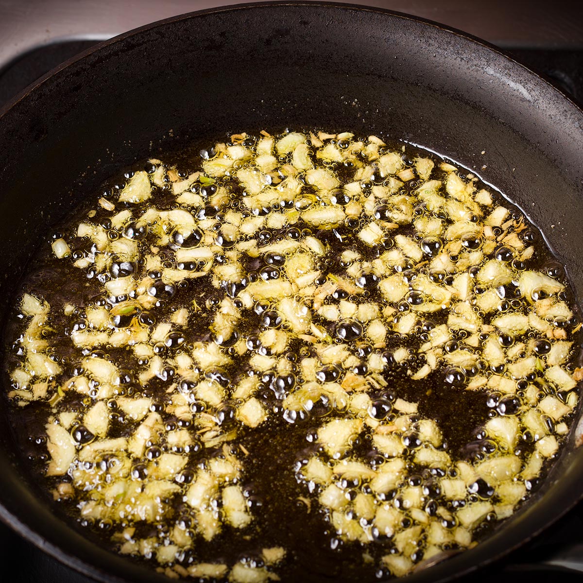 Chopped garlic cooking in hot oil in a small skillet.
