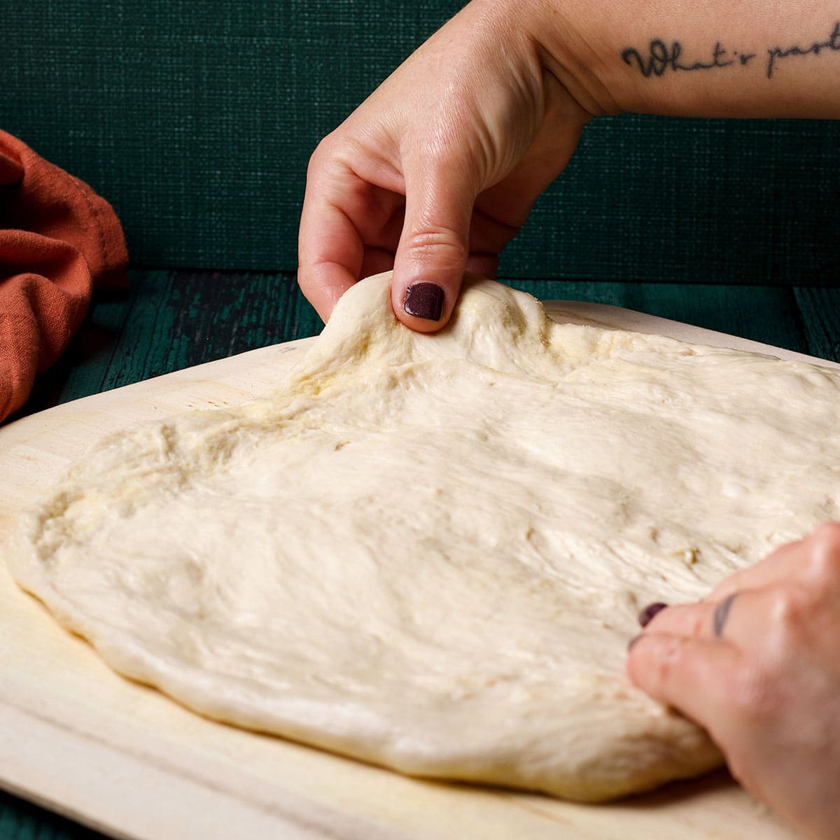 Stretching pizza dough across a pizza peel that's been dusted with semolina flour.
