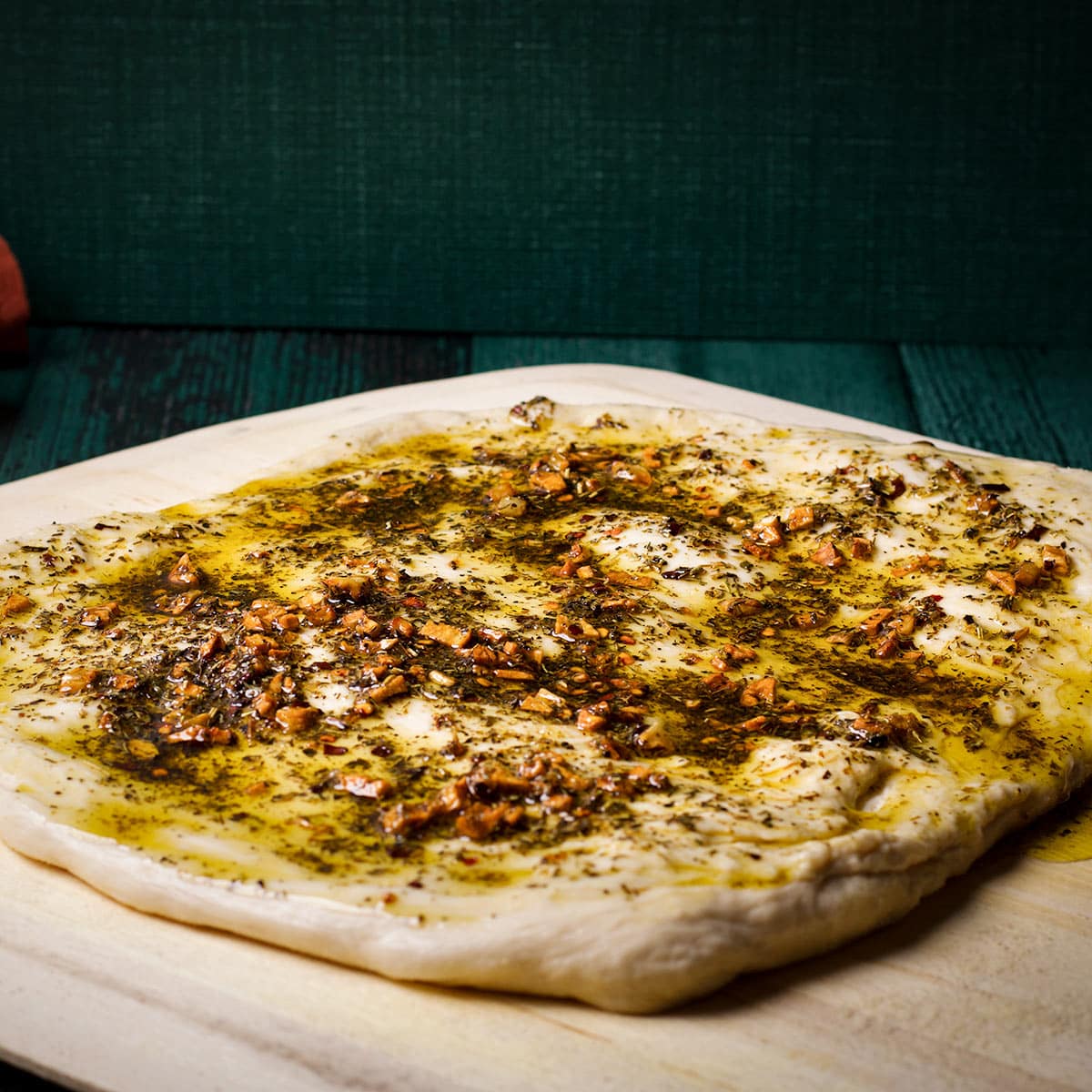 Homemade pizza dough covered in a thick layer of garlic and herb oil.