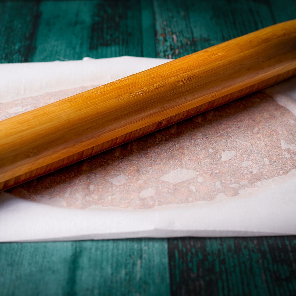 Using a rolling pin to roll cracker dough out into a thin sheet.