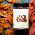 Stacks of gluten free almond cheese crackers on a table next to a container of Naked Almond powder.